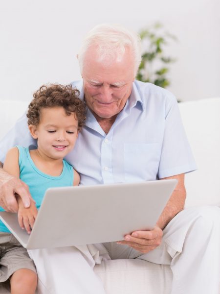 shutterstock_124604611 - happy grandfather with small grandson playing on laptop - different ethnicity